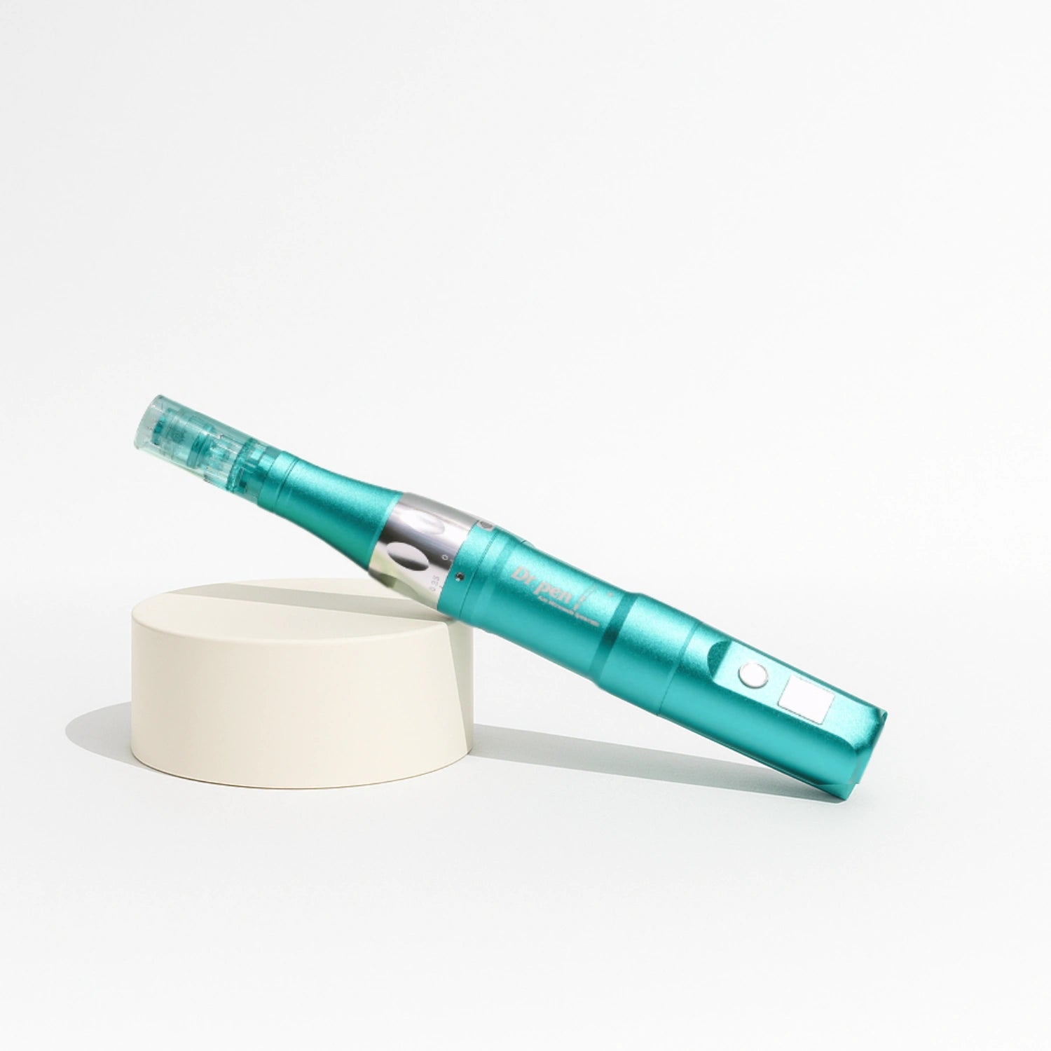 Dr. Pen Ultima A6S microneedling pen in sleek matte teal, resting on a beige cylinder.