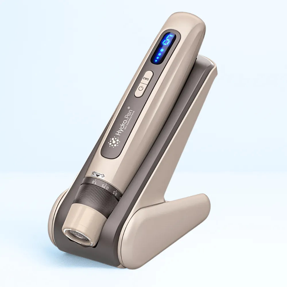 Hydra Pen H5 professional microneedling device in champagne gold with a blue digital display, on its charging stand.